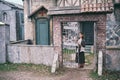 Young brunette woman stands at the gate of an old church. Retro clothes on Halloween Royalty Free Stock Photo