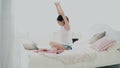 Young brunette woman stretches on a bed. Beautiful girl using laptop during breakfast. Drinking juice and dancing. Royalty Free Stock Photo