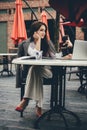 Young freelancer woman using laptop computer sitting at cafe table. Smiling woman working online or studying and Royalty Free Stock Photo