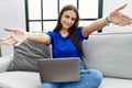 Young brunette woman using laptop at home looking at the camera smiling with open arms for hug Royalty Free Stock Photo