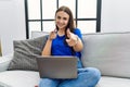 Young brunette woman using laptop at home pointing fingers to camera with happy and funny face Royalty Free Stock Photo