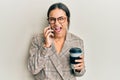 Young brunette woman using smartphone and drinking a cup of coffee celebrating crazy and amazed for success with open eyes Royalty Free Stock Photo