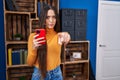 Young brunette woman using smartphone pointing with finger to the camera and to you, confident gesture looking serious Royalty Free Stock Photo