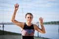 Young brunette woman, wearing black and purple top, standing near volleyball net at the city beach in summer, smiling. Sportswoman Royalty Free Stock Photo