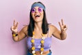 Young brunette woman wearing bohemian and hippie style doing peace symbol smiling and laughing hard out loud because funny crazy