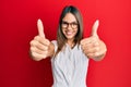 Young brunette woman wearing casual clothes and glasses approving doing positive gesture with hand, thumbs up smiling and happy Royalty Free Stock Photo