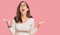 Young brunette woman wearing casual clothes and glasses crazy and mad shouting and yelling with aggressive expression and arms Royalty Free Stock Photo
