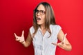 Young brunette woman wearing casual clothes and glasses crazy and mad shouting and yelling with aggressive expression and arms Royalty Free Stock Photo