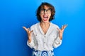 Young brunette woman wearing casual clothes and glasses crazy and mad shouting and yelling with aggressive expression and arms Royalty Free Stock Photo