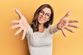 Young brunette woman wearing casual clothes and glasses looking at the camera smiling with open arms for hug Royalty Free Stock Photo