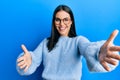 Young brunette woman wearing casual clothes and glasses looking at the camera smiling with open arms for hug Royalty Free Stock Photo