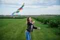 Young brunette woman, wearing casual clothes green t-shirt, playing with colorful kite on green field meadow in summer, running, Royalty Free Stock Photo