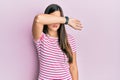 Young brunette woman wearing casual clothes over pink background covering eyes with arm, looking serious and sad Royalty Free Stock Photo