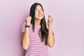 Young brunette woman wearing casual clothes over pink background excited for success with arms raised and eyes closed celebrating Royalty Free Stock Photo