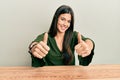 Young brunette woman wearing casual clothes sitting on the table approving doing positive gesture with hand, thumbs up smiling and Royalty Free Stock Photo