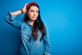 Young brunette woman wearing casual denim shirt over blue isolated background confuse and wondering about question Royalty Free Stock Photo