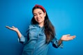 Young brunette woman wearing casual denim shirt over blue isolated background smiling showing both hands open palms, presenting Royalty Free Stock Photo