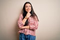 Young brunette woman wearing casual striped shirt over isolated background with hand on chin thinking about question, pensive Royalty Free Stock Photo