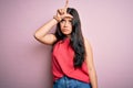 Young brunette woman wearing casual summer shirt over pink isolated background making fun of people with fingers on forehead doing Royalty Free Stock Photo