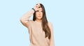 Young brunette woman wearing casual winter sweater making fun of people with fingers on forehead doing loser gesture mocking and