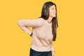 Young brunette woman wearing casual winter sweater suffering of backache, touching back with hand, muscular pain Royalty Free Stock Photo