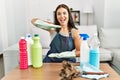 Young brunette woman wearing cleaner apron and gloves cleaning at home gesturing with hands showing big and large size sign, Royalty Free Stock Photo