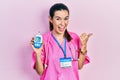 Young brunette woman wearing doctor uniform holding glucometer pointing thumb up to the side smiling happy with open mouth Royalty Free Stock Photo