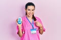 Young brunette woman wearing doctor uniform holding glucometer smiling happy pointing with hand and finger Royalty Free Stock Photo