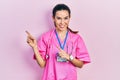 Young brunette woman wearing doctor uniform and stethoscope smiling and looking at the camera pointing with two hands and fingers Royalty Free Stock Photo