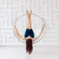 Young brunette woman wearing elegant blue dress levitate on round glass chair