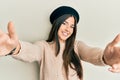 Young brunette woman wearing french look with beret looking at the camera smiling with open arms for hug Royalty Free Stock Photo