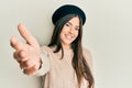 Young brunette woman wearing french look with beret smiling friendly offering handshake as greeting and welcoming