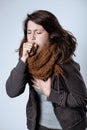 Young brunette woman wearing jacket and scarf and coughing