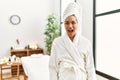 Young brunette woman wearing towel and bathrobe standing at beauty center afraid and shocked with surprise expression, fear and