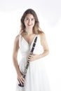 Young brunette woman in white dress holds clarinet in studio and