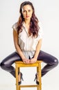 A young brunette woman in white shirt posing on a chair aggressively