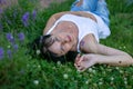 Horizontal closeup portrait of a young woman lying on grass in a park wearing casual clothes