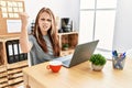 Young brunette woman working at the office with laptop angry and mad raising fist frustrated and furious while shouting with anger Royalty Free Stock Photo