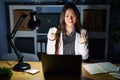 Young brunette woman working at the office at night with laptop doing money gesture with hands, asking for salary payment, Royalty Free Stock Photo