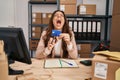 Young brunette woman working at small business ecommerce cutting credit card angry and mad screaming frustrated and furious, Royalty Free Stock Photo