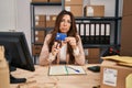 Young brunette woman working at small business ecommerce cutting credit card depressed and worry for distress, crying angry and Royalty Free Stock Photo