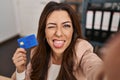 Young brunette woman working at small business ecommerce holding credit card sticking tongue out happy with funny expression Royalty Free Stock Photo