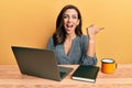 Young brunette woman working using computer laptop pointing thumb up to the side smiling happy with open mouth Royalty Free Stock Photo