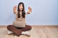 Young brunette woman working using computer laptop sitting on the floor doing stop gesture with hands palms, angry and frustration Royalty Free Stock Photo