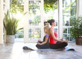 Young brunette woman with little daughter in a sporty uniform doing yoga on the terrace of a house