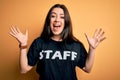 Young brunette worker woman wearing staff t-shirt as uniform over yellow isolated background very happy and excited, winner Royalty Free Stock Photo