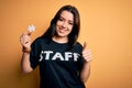 Young brunette worker woman wearing staff t-shirt as uniform showing puzzle piece as teamwork happy with big smile doing ok sign, Royalty Free Stock Photo