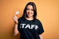 Young brunette worker woman wearing staff t-shirt as uniform showing puzzle piece as teamwork with a happy face standing and Royalty Free Stock Photo