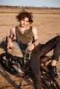 Young brutal man laying on his motorcycle and holding bottle