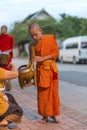 Young buddhist monk getting alms